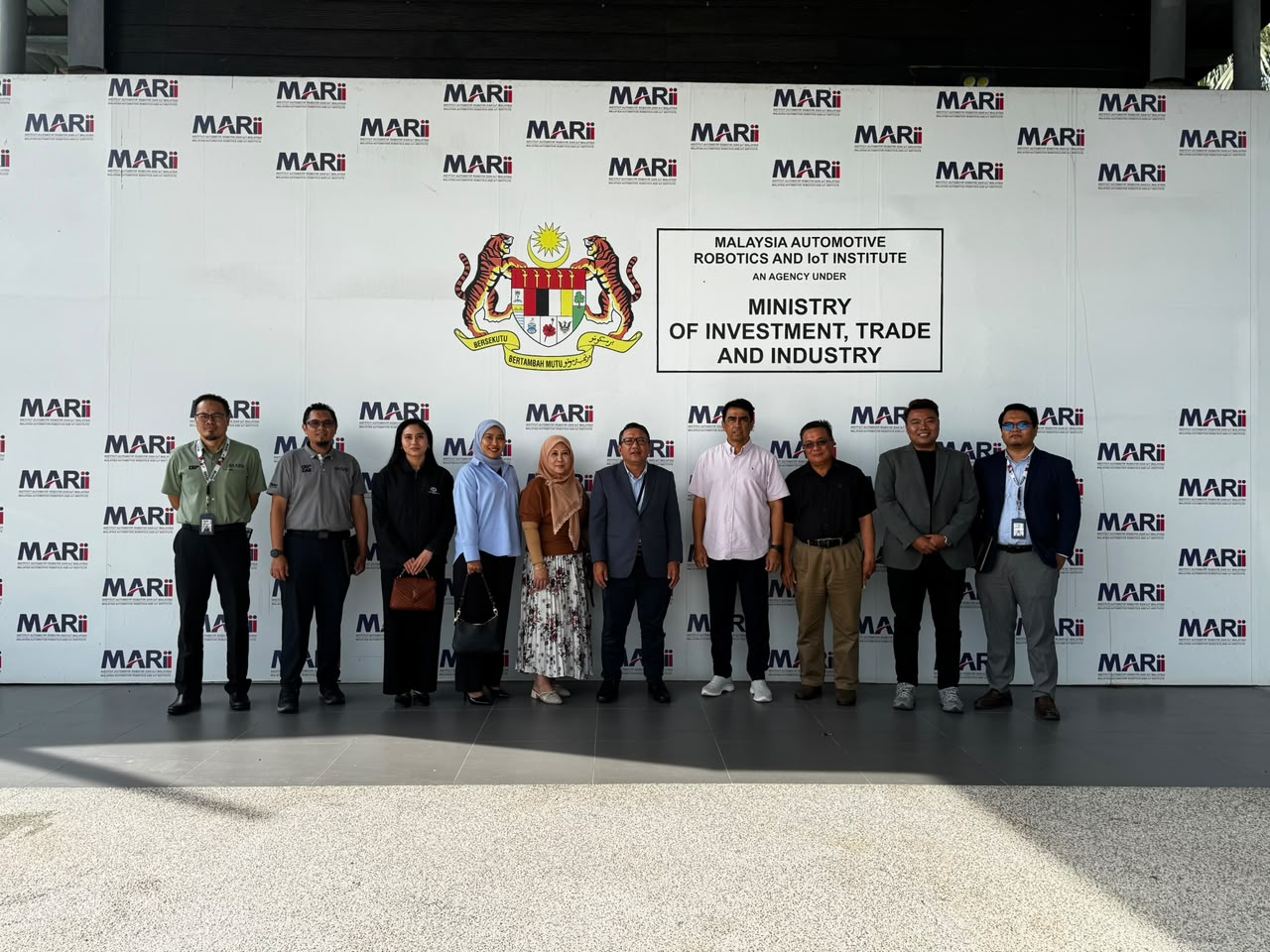 A group of ten standing in front of a MARii backdrop naming it an agency under the Ministry of Investment, Trade and Industry.