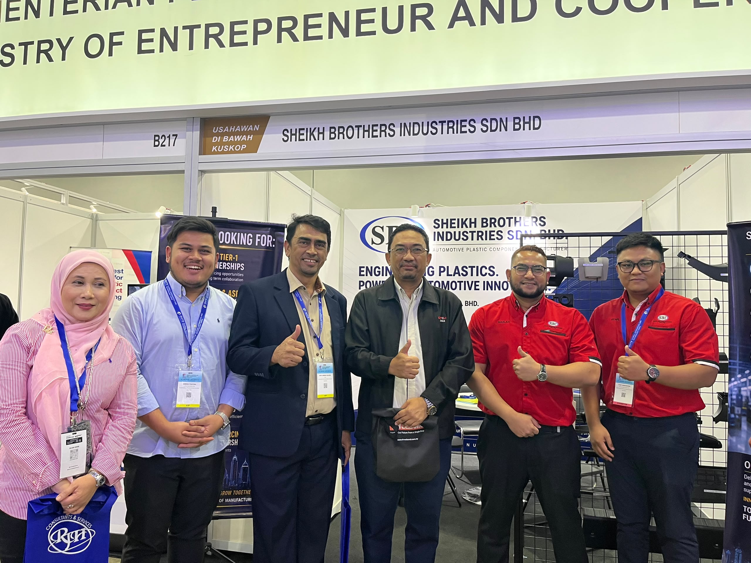 Seven people standing in front of SBI's stand, B217, and its banners.