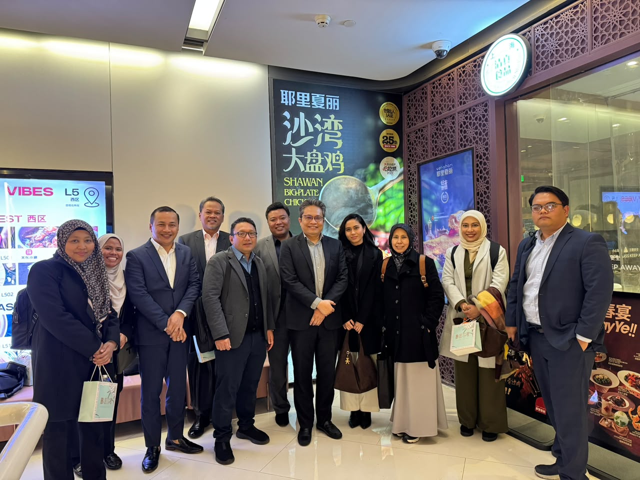 Twelve members of the Malaysian delegation standing together in a shopping centre in Shanghai.