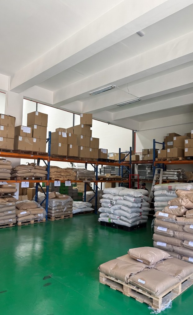 Sacks of plastic resin on pallets and cartons on racking in the material store.