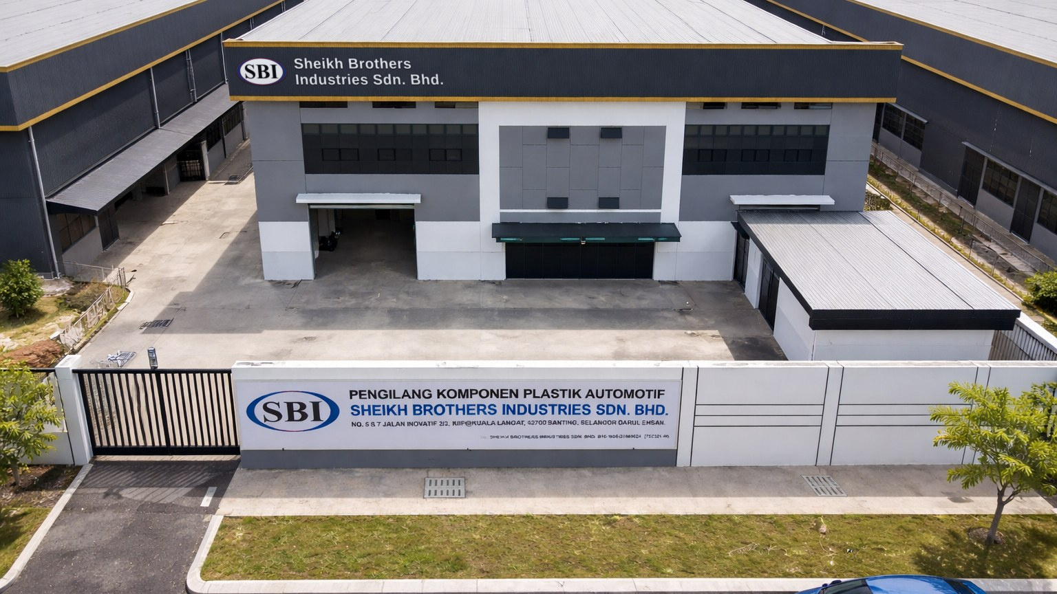 SBI's plant from the air: a grey two-storey factory with a white boundary wall carrying the sign Pengilang Komponen Plastik Automotif, Sheikh Brothers Industries Sdn. Bhd.